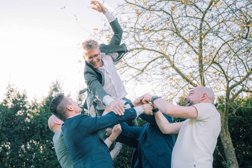Vrienden gooien de bruidegom in de lucht